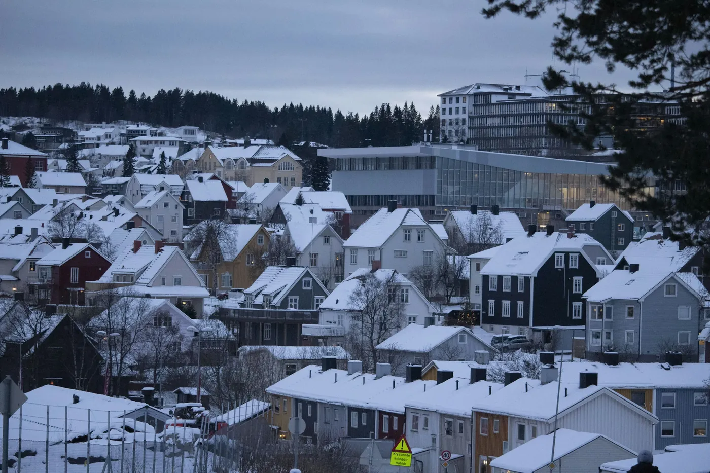 Snow-covered rooftops of Narvik on the hillside, with a modern glass building and apartment blocks behind